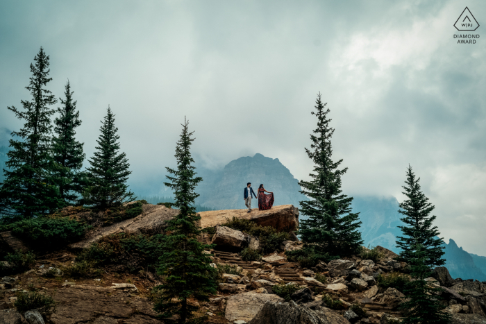 Eine Lifestyle-Fotosession für Paare am Moraine Lake in Alberta, Kanada, bei der die beiden einen wunderschönen Morgen und die Aussicht auf die Berge und Bäume genießen