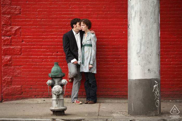 Little Five Points post proposal engagement session with an Atlanta wedding photographer showing the Couple posed with fire hydrant and red brick wall