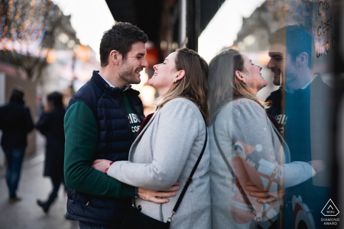 Ritratti post proposta di Agen da una sessione di fidanzamento di coppia Lot-et-Garonne per le strade urbane della città con riflessi sul vetro della vetrina