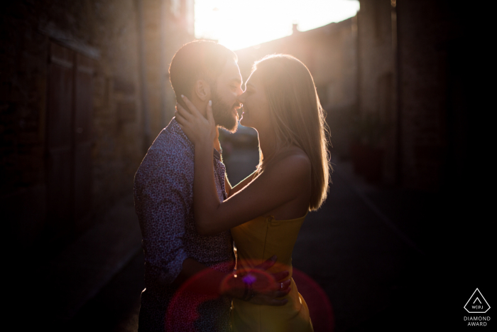 Séance de portrait après proposition Oingt avec un photographe de fiançailles d'Auvergne-Rhône-Alpes d'un couple de France montrant La fille embrasse le garçon dans une vieille ville de pierre en France