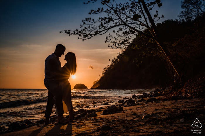 Playa Herradura publica retratos de propuesta por un fotógrafo de bodas de Marina Los Sueños de una feliz pareja de Costa Rica en una silueta durante la puesta de sol en su sesión de compromiso