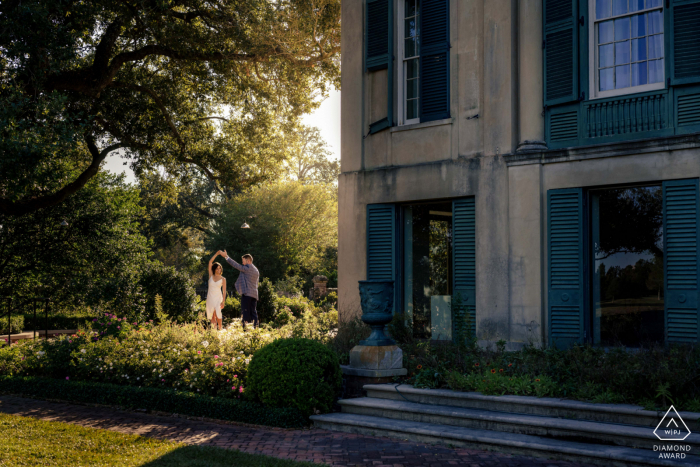 Fotografía de propuesta posterior a Longue Vue House and Gardens que muestra a una pareja sonriente de Nueva Orleans durante una escena de The Notebook con cuento de hadas bailando bajo la luz del sol