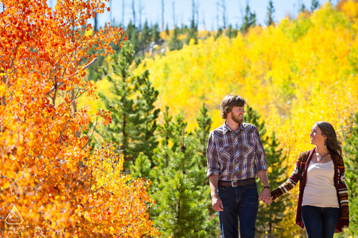 Fort Collins post proposal portrait photos of a happy Colorado couple walking a nature trail in the Fall with trees showing aspen colors 