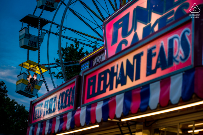 Fotografia della proposta di Arlington County Fair che mostra una coppia sorridente della Virginia che ride insieme mentre cavalca la giostra vicino al supporto della torta dell'imbuto