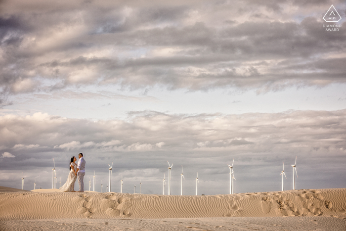 Dunas de Salinas Engagement. A young Rio Grande do Sul couple posing during a picturesque beach pre wedding portrait session with windmills in the background Dunas de Salinas Engagement. A young Rio Grande do Sul couple posing during a picturesque beach pre wedding portrait session with windmills in the background