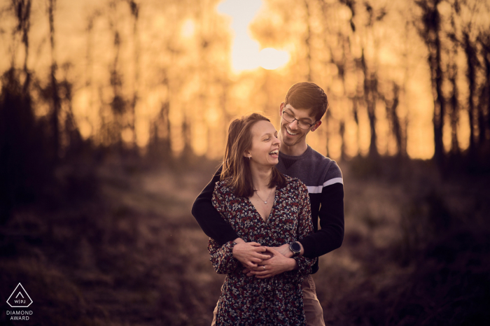 Fotos de compromiso de Francia. Pareja de Forêt d'Halatte posando al atardecer, mientras el futuro novio sostiene en brazos a su futura esposa