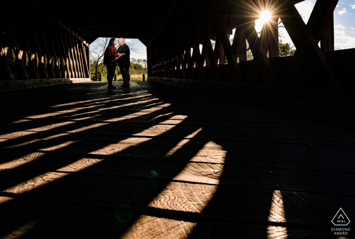 Eine romantische Verlobungs-Session im Gettysburg National Military Park, die entsteht, wenn das Paar kurz vor Sonnenuntergang auf einer überdachten Brücke posiert