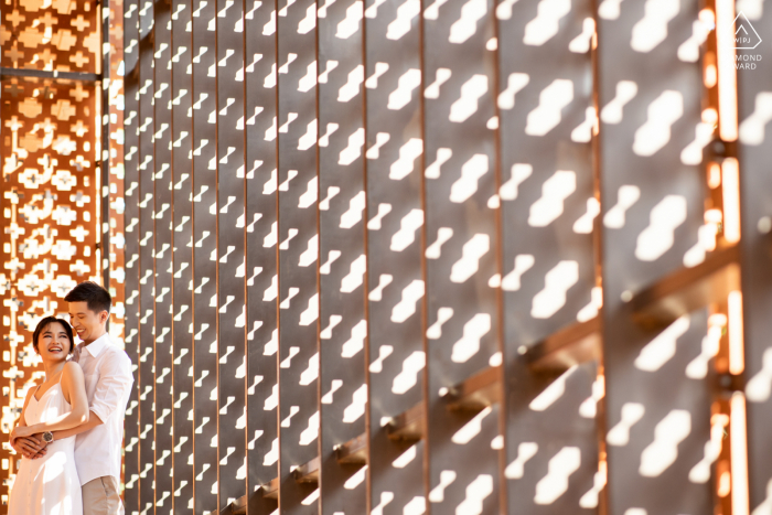 Une séance de fiançailles romantique à Bangkok, en Thaïlande, avec des motifs audacieux créés par la lumière du soleil et les ombres sur le mur