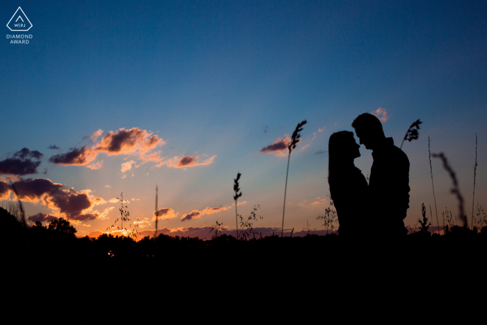 Fiançailles françaises. Un jeune couple Tramoyes posant lors d'une séance de portrait avant le mariage juste après le coucher du soleil, et se tenir avant de s'embrasser