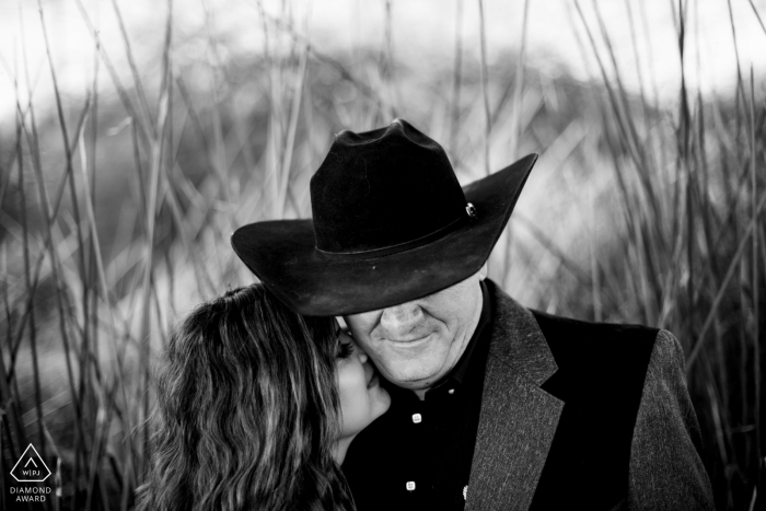 Fotos de compromiso de Arizona. Pareja de Gilbert posando bajo el sombrero de vaquero del hombre en BW