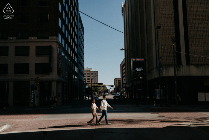 Texas Engagement Photos. Dallas couple posing as they hold hands and walk across the street Texas Engagement Photos. Dallas couple posing as they hold hands and walk across the street