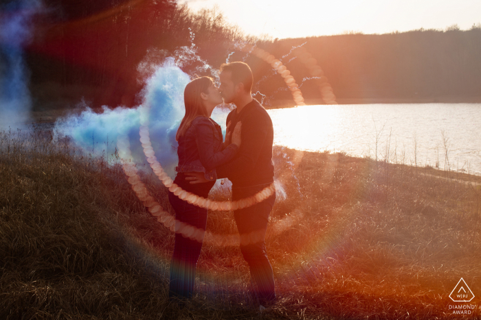 Fotos de noivado Epinal. Um casal Vosges posar à beira da água à luz do sol da tarde com granadas de fumaça