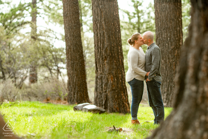 Uma sessão de fotos pré-casamento de Galena Forest, Nevada, mostrando o casal se beijando na chuva