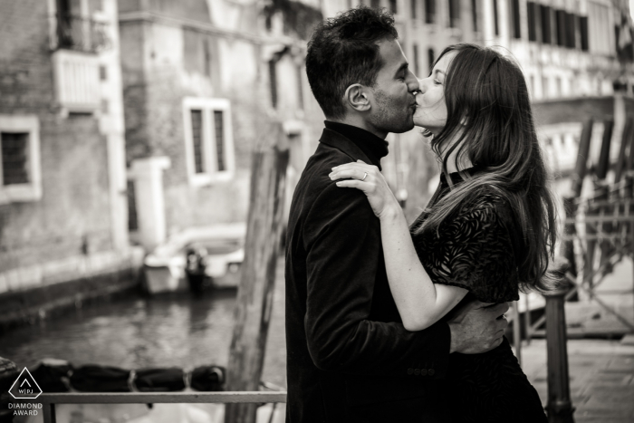 Verlobung in Venedig. Ein junges italienisches Paar posiert während einer Portrait-Session vor der Hochzeit in BW am Kanal