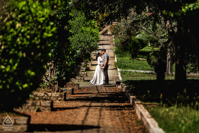 Sesión de fotos de compromiso de Juiz de Fora en Minas Gerais con una pareja besándose en un camino de tierra en el huerto