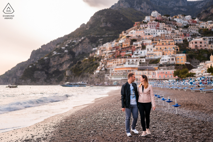 Romantyczna sesja narzeczeńska w Positano na Wybrzeżu Amalfi w Salerno stworzona na plaży, gdy para spaceruje razem o zachodzie słońca