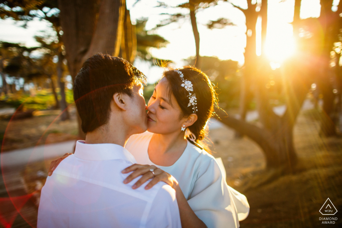 Impegno della California del Nord. Una giovane coppia di San Francisco in posa durante una sessione di ritratto prima del matrimonio con Un adorabile bacio al sole dorato