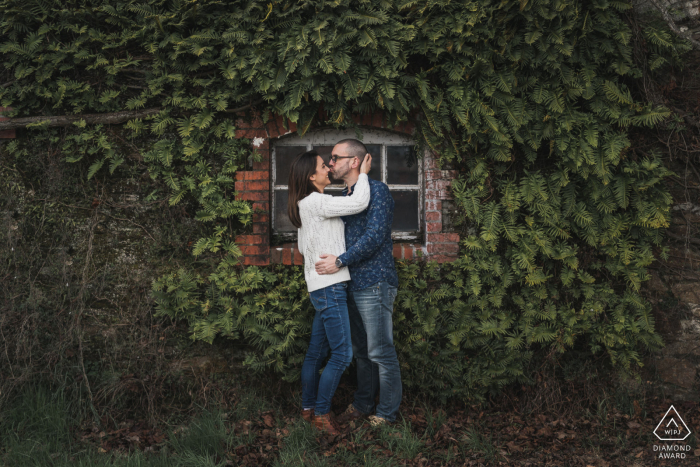 Fotos de compromiso Vertou. Una pareja de Loire-Atlantique posa junto a una ventana rodeada de hiedra en la pared