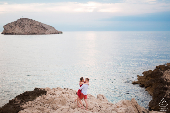 She said yes, post marriage proposal picture session in Les Goudes, Marseille showing The couple approached for a kiss just above the sea