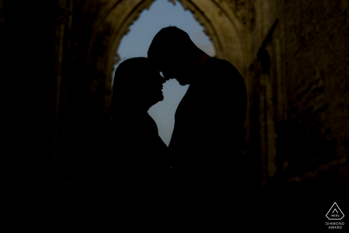 Ein Verlobungsfoto der Charentes Maritimes nach dem Heiratsantrag, das eine Silhouette eines Paares zeigt, das die Köpfe durch die Ruinen einer Kirche berührt