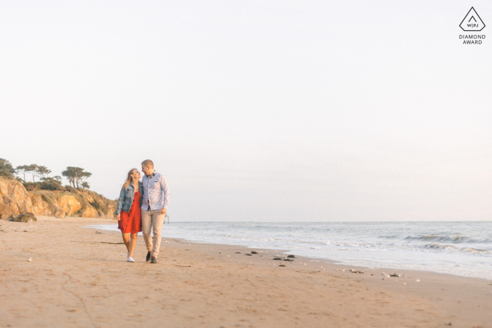 Ein Save-the-Date in Pornic. Loire-Atlantique-Porträt des jungen Paares, das nach Sonnenuntergang am Strand spazieren geht