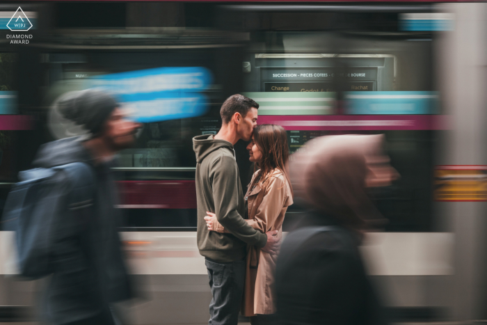 Ein Save the Date in Nancy. Frankreich-Porträt eines küssenden Paares mit einer Straßenbahn und vorbeifahrenden Menschen