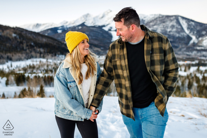 Eine Verlobungsfotosession nach dem Heiratsantrag in Frisco, Colorado, während das Paar Händchen haltend durch den Winterschnee läuft