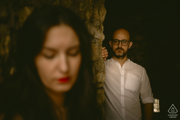 An after the marriage proposal Brescia Castle engagement photograph in warm tones with a couple by a stone wall