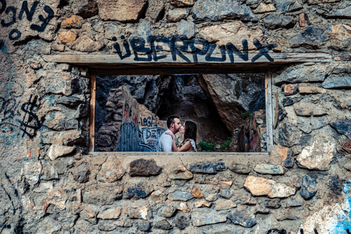 Ha detto di sì, sessione fotografica dopo la proposta di matrimonio a Cahorros de Monachil, Granada, all'interno di un edificio in pietra con graffiti sopra l'apertura della finestra