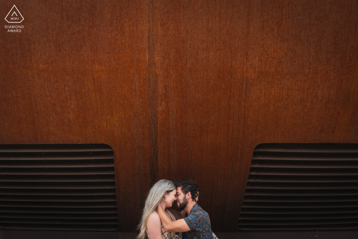 Nach dem Heiratsantrag Verlobungsfotosession in Groningen, Niederlande, mit dem Paar, das sich an einer riesigen burgunderroten Wand umarmt