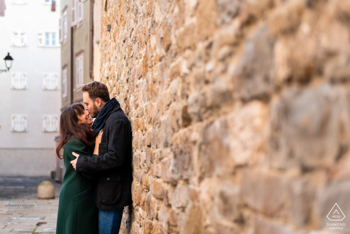 Después de la propuesta de matrimonio Fotografía de compromiso de Trieste con un abrazo junto a la pared de piedras.