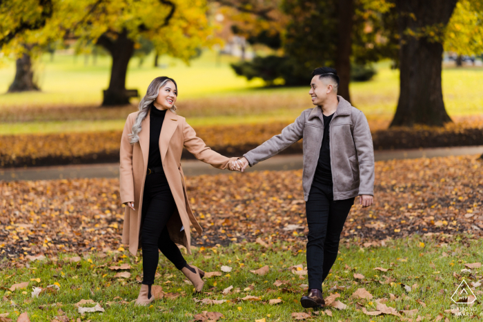 Um casal moderno de Melbourne posa no parque durante o outono para um retrato de anúncio de seu noivado em Victoria