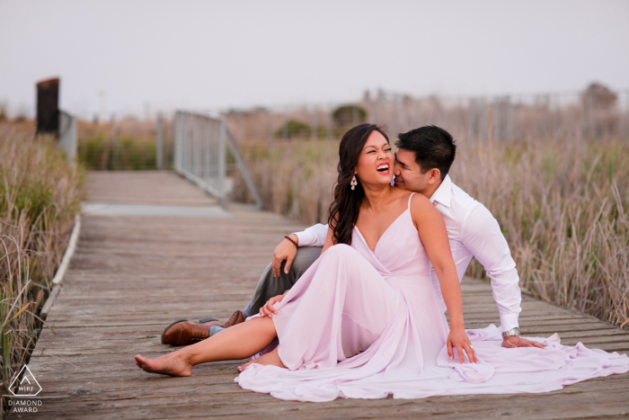 Una pareja moderna de Alviso se sienta en el paseo marítimo para un retrato de anuncio de su compromiso de boda en California