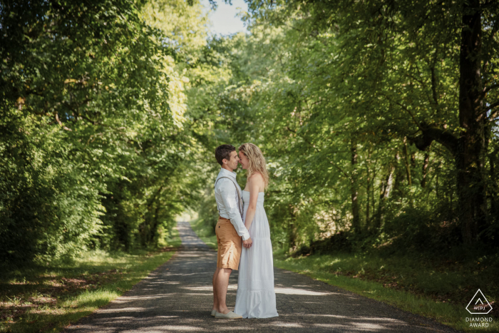 A Marciac couple with a casual style poses in the middle of the road face to face for France engagement announcement portraits A Marciac couple with a casual style poses in the middle of the road face to face for France engagement announcement portraits