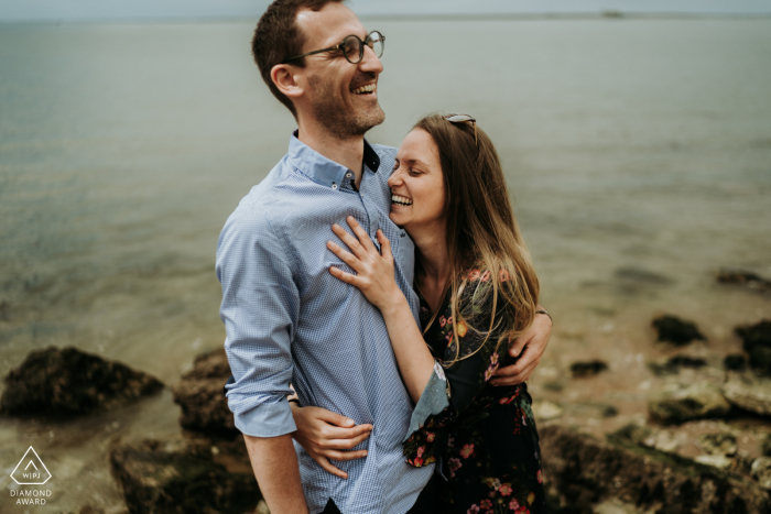 Una pareja relajada de Ile d'Aix posa junto al agua para un anuncio casual retrato de su compromiso en Charente-Maritime