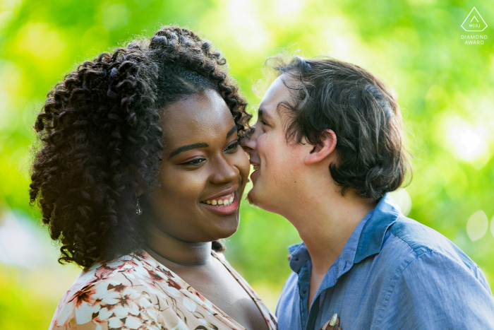 Georgia couple poses as he is Whispering in her ear for fun portraits to announce their Pine Lake engagement