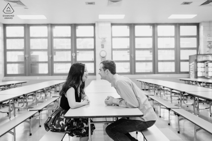 A Brooklyn indoor portrait shows a unique way this newly engaged couple is announcing their NYC engagement at a private school Sitting in the lunch room where they first met as teachers 