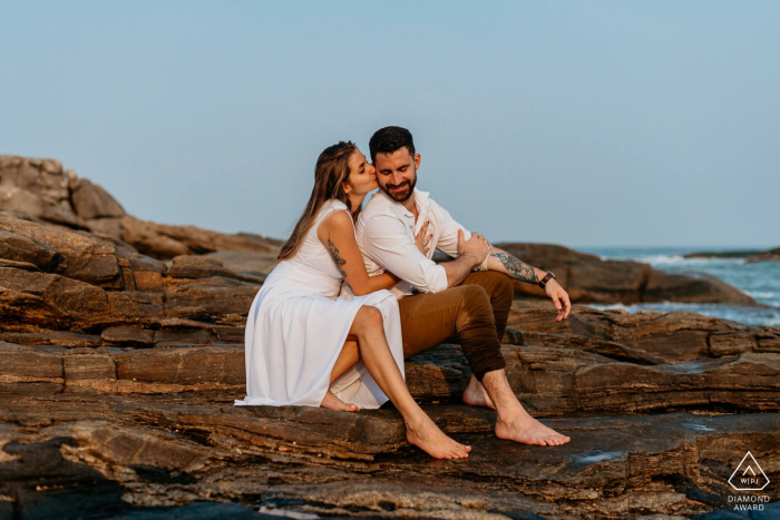 Ein Rio das Ostras-Paarabenteuer zusammen für eine moderne Portrait-Session zur Ankündigung der Verlobung in Rio de Janeiro auf den Felsen an den Meereswellen auf See