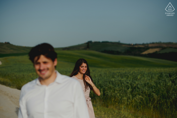 A newly engaged Siena couple poses in the outdoors in the Tuscany countryside for an Italy engagement announcement portrait A newly engaged Siena couple poses in the outdoors in the Tuscany countryside for an Italy engagement announcement portrait