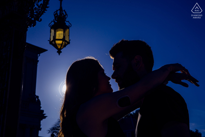 A newly engaged Stanislas couple poses near a street lamp for a Nancy silhouette engagement announcement portrait