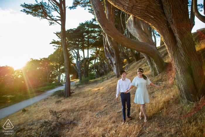 Una pareja de San Francisco camina felizmente por el bosque de cipreses para tomar fotos para anunciar su compromiso