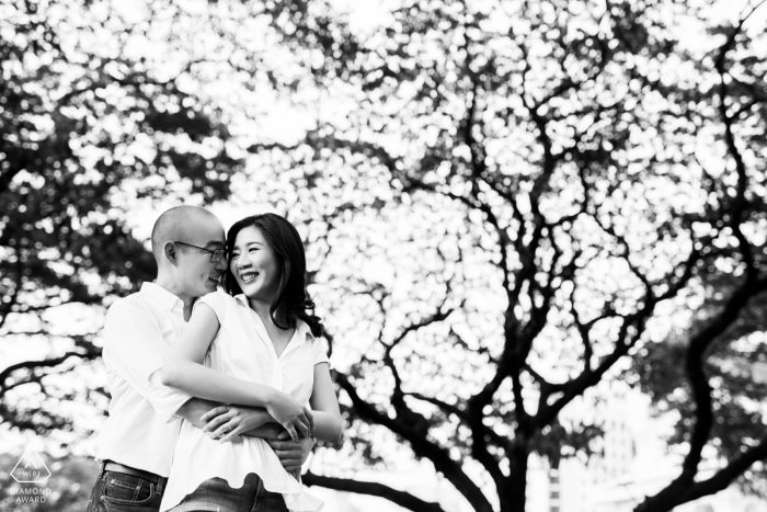 Fun Bangkok engagement announcement picture in nature with a background of tree branches and leaves