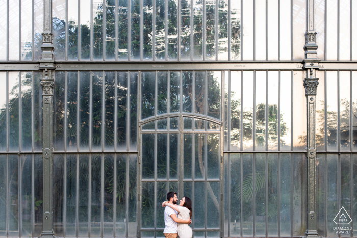 Idée de photo d'annonce de fiançailles au Parc de la Tête d'Or à Lyon, en France, créée alors que le couple se serre dans ses bras près de la serre du parc