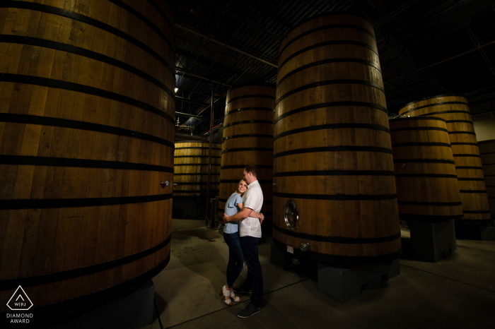 Fort Collins engagement announcement photo idea at the New Belgium Brewery created as the Couple enjoys a minute together amongst the large beer sour casks at a local brewery Fort Collins engagement announcement photo idea at the New Belgium Brewery created as the Couple enjoys a minute together amongst the large beer sour casks at a local brewery