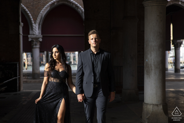 Idea de foto de anuncio de compromiso de Venecia en el mercado de pescado de Rialto con la pareja italiana caminando en traje formal negro