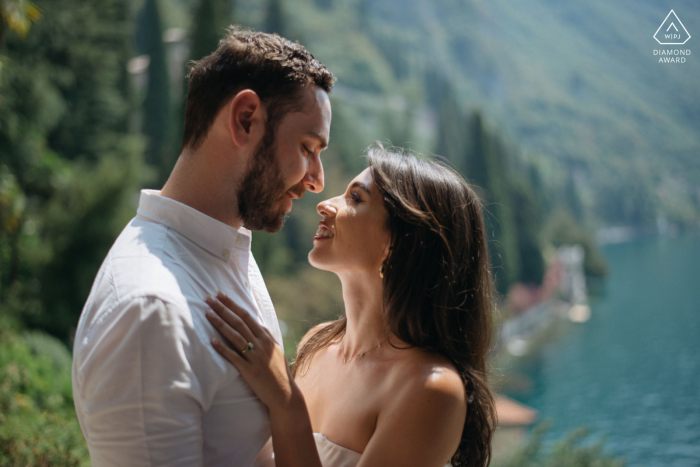 Lake Como lifestyle engagement photography of a couple at the Villa Monastero overlooking the lake in the sunlight A romantic lakeside engagement shoot captured the love between a couple at a picturesque villa