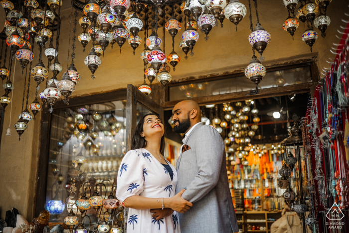 Fotografía de compromiso de estilo de vida de Old Dubai Al Seef de una pareja abrazándose en una tienda de lámparas Fotografía de compromiso de estilo de vida de Old Dubai Al Seef de una pareja abrazándose en una tienda de lámparas