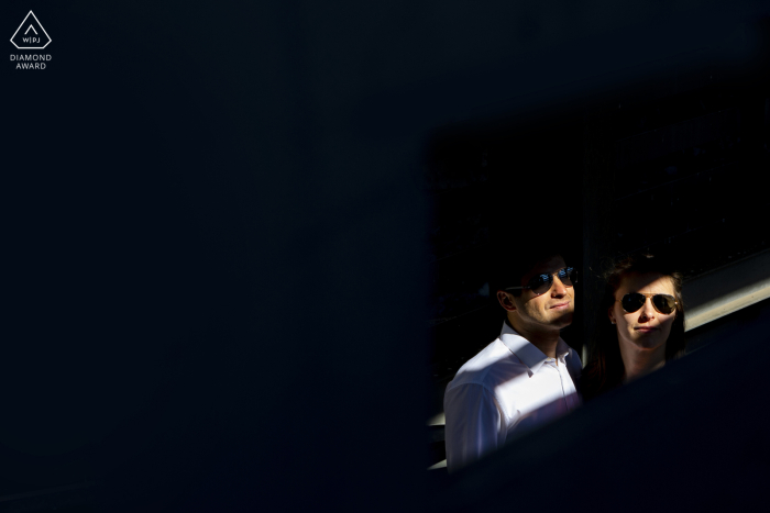 Una sesión de retratos de compromiso de estilo de vida en el lago Iseo, Italia, para una pareja que posa en los rayos de luz con gafas de sol Una sesión de retratos de compromiso de estilo de vida en el lago Iseo, Italia, para una pareja que posa en los rayos de luz con gafas de sol