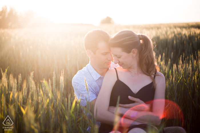 A lifestyle engagement portrait session in Oytier-Saint-Oblas for a couple in Isère, France hugging in a wheat field near their reception venue 