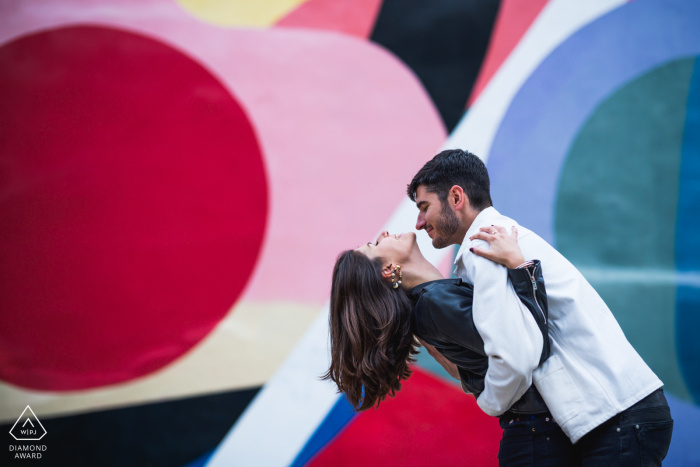 A lifestyle engagement portrait session in Toulouse for a French couple dipping and dancing before a colorful wall mural